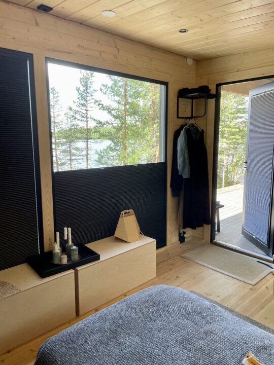 Dark pleated blackout blinds covering windows in a cozy wooden cabin bedroom with a fireplace, blocking out light for a calm and private atmosphere