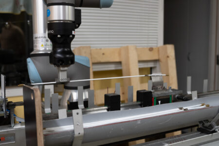 Robotic working on precision parts for blinds manufacturing in an industrial setting.