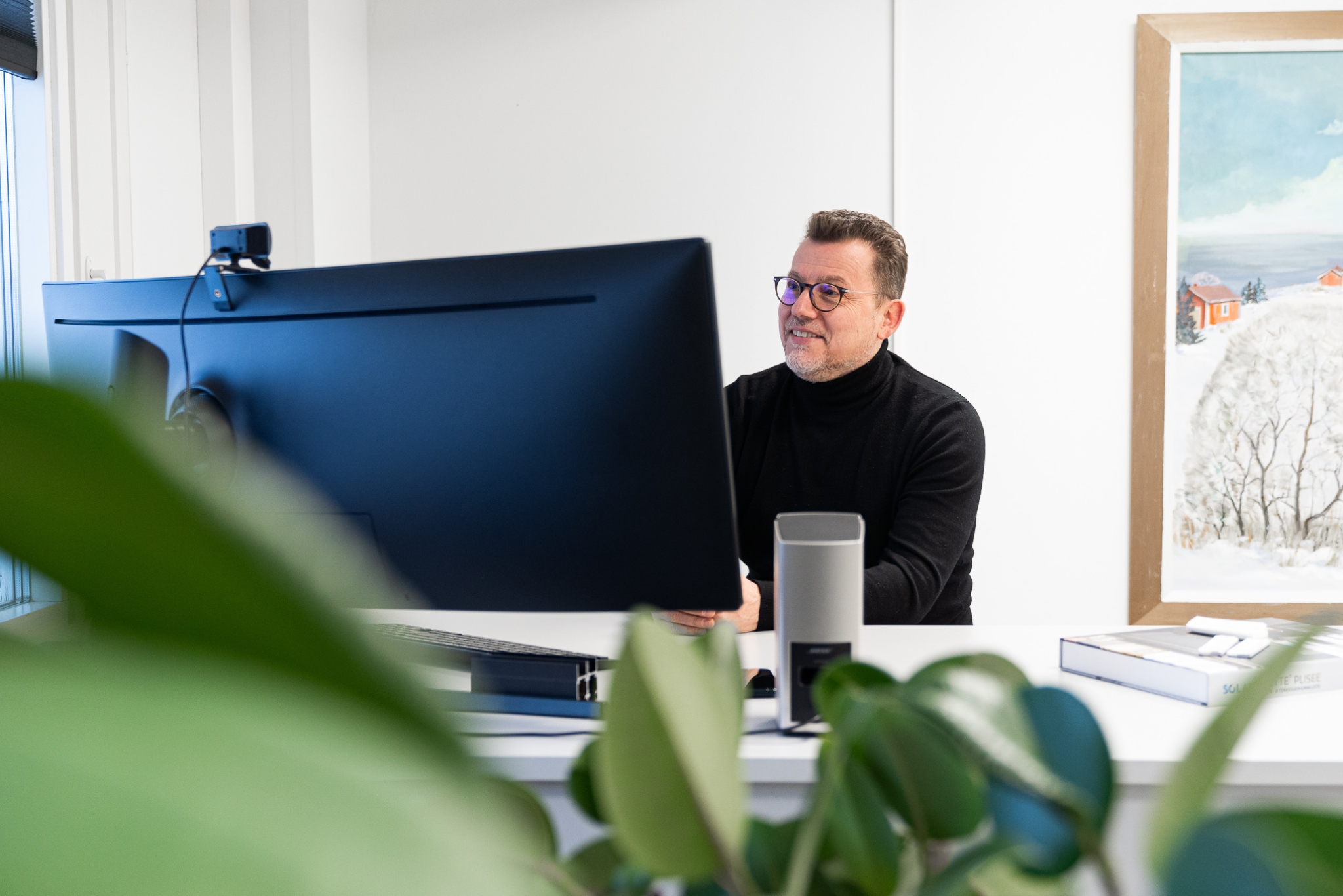 En man ger expertrådgivning via videosamtal från sitt skrivbord och hjälper en kund att välja rätt persienner för hemmet.