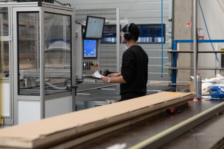Employee monitoring and controlling a machine via a digital interface in a modern factory environment.