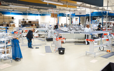 Spacious factory floor in Finland where employees assemble and handle blinds using automated equipment.