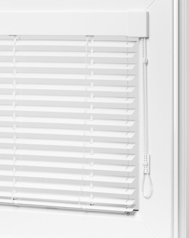 Close-up of white venetian blinds mounted on a window, with horizontal slats and a pull cord for adjusting light and privacy